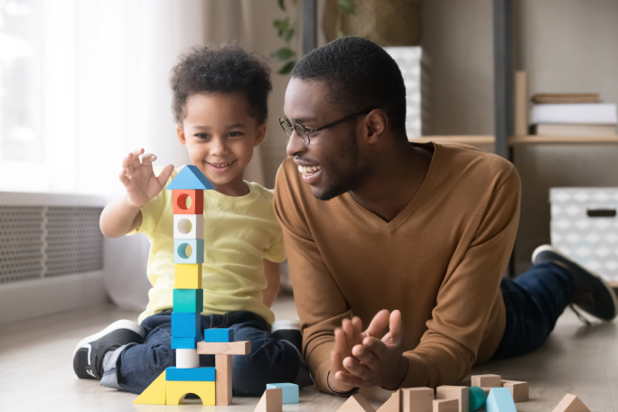 Father and child playing with blocks on the floor